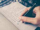 Person writing checklist on book